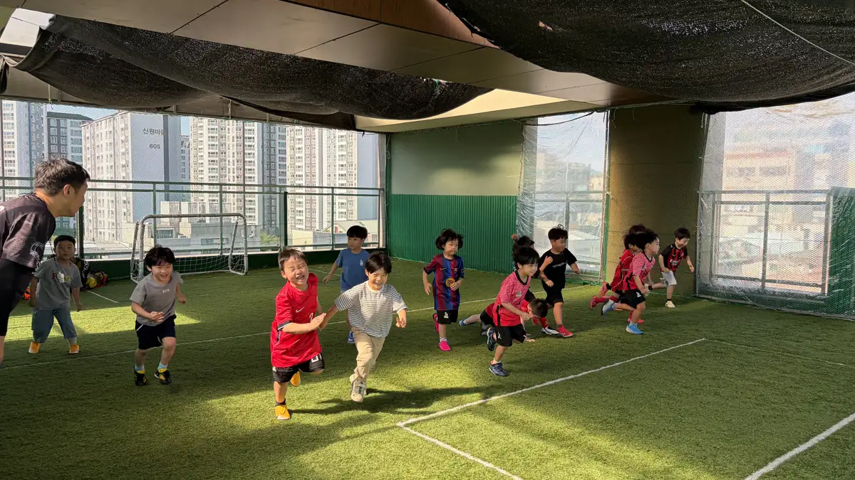 옥상 인조잔디 구장에서 공을 몰고 달리는 축구 수업